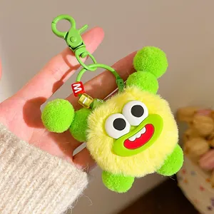 Detail of yellow fuzzy monster keychain with large eyes, red lips and green lobster clasp
