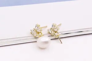 Detailopname van de gouden S925 zilveren strikoorbellen met zirkonia en witte parel