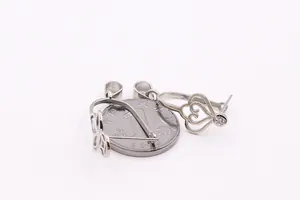 Macro shot of silver hollow heart-shaped pendants with zircons and coin for size scale