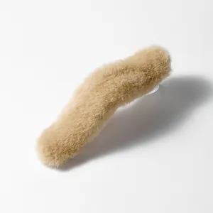 Detailopname van een grote beige pluche haarklem met zachte imitatiebont textuur