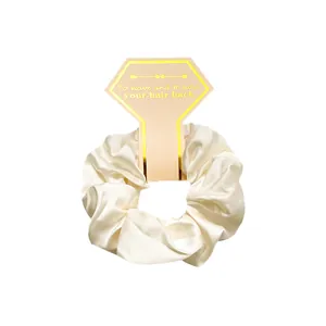 Detail of cream silk satin scrunchie on premium card with gold arrow pattern