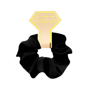 Detail of a black satin silk scrunchie on a decorative hexagonal hair tie card holder