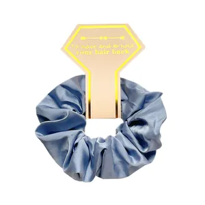 Close-up of light blue satin scrunchie with a gold-edged decorative display card