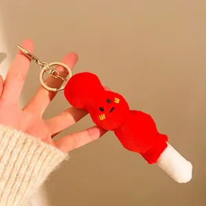 Gros plan d'un porte-clés en peluche rouge tenu à la main sur un fond chaleureux