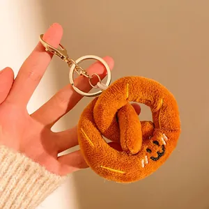 Détail du porte-clés bretzel en peluche avec visage souriant et fermoir doré