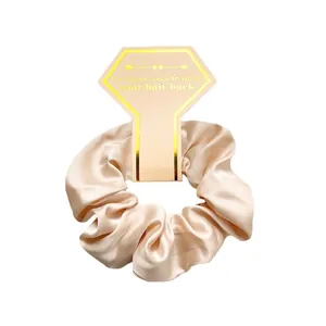 Elegant champagne gold satin scrunchie displayed on a pink decorative card with a silk texture