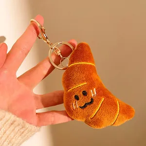 Gros plan d'un porte-clés croissant en peluche avec visage brodé dans la main