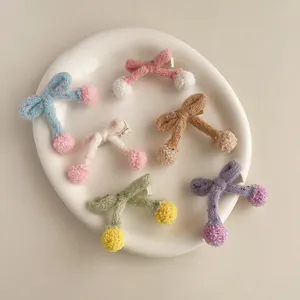 Lot de six barrettes à nœuds en tricot avec pompons doux dans un plat en céramique