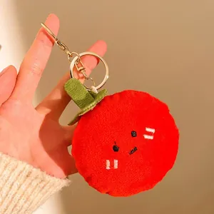 Gros plan d'un porte-clés en peluche rouge avec feuille verte et mousqueton en métal doré