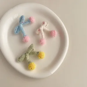 Détails de trois barrettes à cheveux tricotées avec pompons sur une assiette en céramique