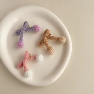 Gros plan de trois barrettes à nœuds tricotés avec pompons sur un plateau blanc