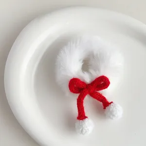Detail of white plush hair scrunchie with red knit bow and soft pompom charms
