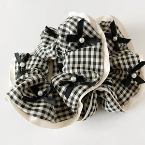 Détail d'un chouchou à carreaux avec petits nœuds noirs et perles élégantes