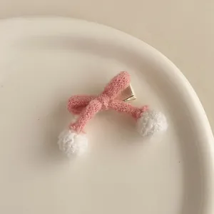 Détail de la pince à cheveux noeud tricoté rose avec pompons blancs et clip bec de canard