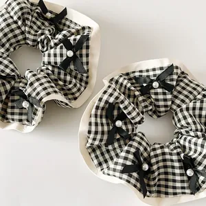 Détail de chouchous à carreaux avec rubans noirs et perles pour la coiffure