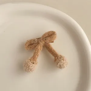 Détail de la barrette à nœud tricoté avec pompons en peluche et pince crocodile