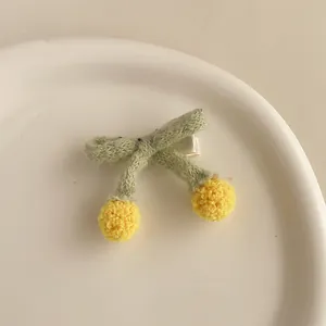 Détail de la pince à cheveux en tricot avec feuilles vertes et pompons jaunes