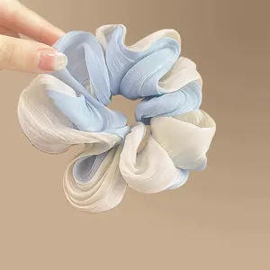 Detail of blue and beige gradient organza scrunchie with soft pleated fabric texture