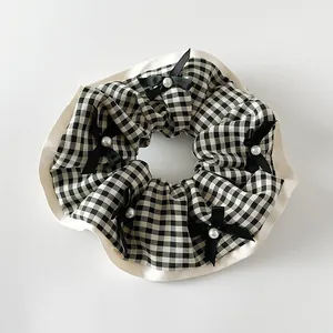 Détail d'un chouchou à carreaux avec bord en satin et petits nœuds aux perles