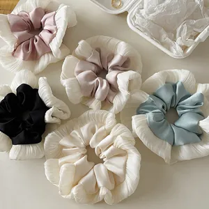 Elegant satin and lace scrunchies in various pastel colors on a minimal desk background