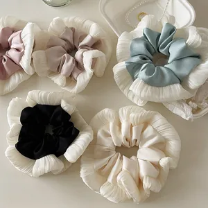 Detailed view of layered lace and satin scrunchies in various pastel colors