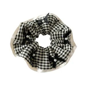 Chouchou vichy rétro avec nœuds noirs et perles sur fond blanc minimaliste