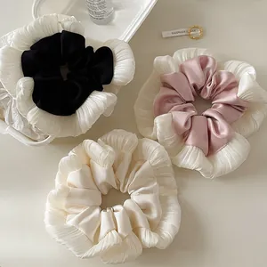Three oversized satin scrunchies in black, pink, and beige with white lace edge detail