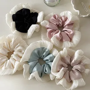Set of five lace satin scrunchies in pastel colors laid on a clean minimalist surface
