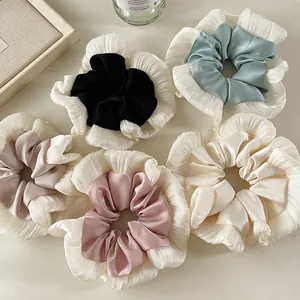 Detailed top view of five oversized lace and satin hair scrunchies in pastel Morandi tones