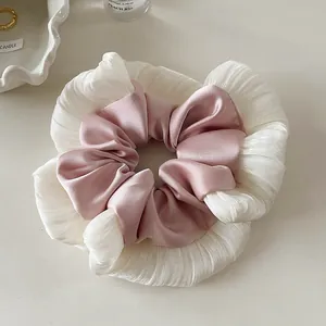 Close-up of pink satin scrunchie with white lace trim on a minimalist table setting