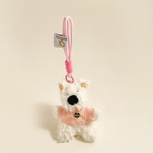 Detailopname van witte pluche beer sleutelhanger met roze trui en gouden bedel