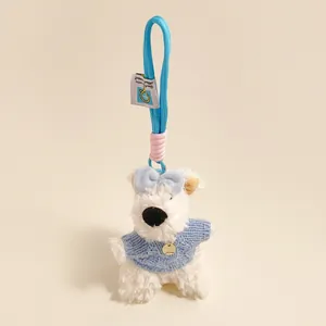 Detail van een pluche witte puppy met blauwe trui en een geweven ophangkoord