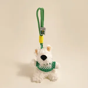 Detail van witte pluche honden-sleutelhanger met groene gebreide trui en hartpatroon