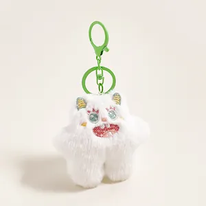 Detailopname van witte pluche monster-sleutelhanger met groene borduurogen en metalen haak