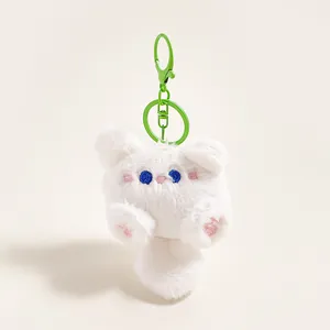 Detail van witte pluche kattenhanger met blauwe ogen en groene metalen haak