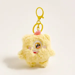 Detail van gele pluche monster sleutelhanger met geborduurd oog en metalen ring