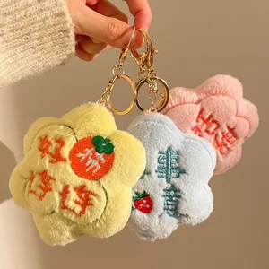 Detailed view of three colorful plush flower keychains with festive embroidery and gold hooks