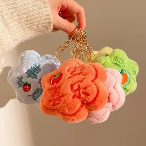 Close-up of colorful plush flower charms with gold keychains and lucky embroidery