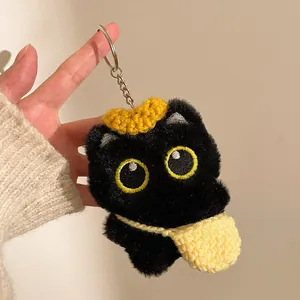 Détail d'un porte-clés chat noir en peluche avec couronne jaune et mini sac à bandoulière
