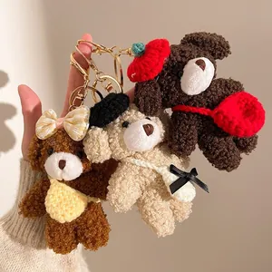 Porte-clés ours en peluche marron et crème avec chapeaux et nœuds, porté à la main
