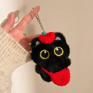 Détail du porte-clés chat noir en peluche avec bonnet rouge et yeux brodés jaunes