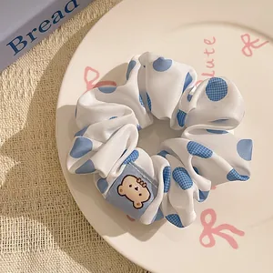 Detailed close-up of a blue polka dot scrunchie featuring a cute cartoon bear patch