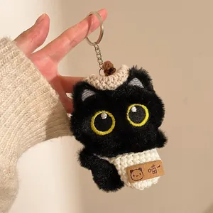 Détail d'un porte-clés chat noir en peluche avec yeux jaunes et bonnet en tricot
