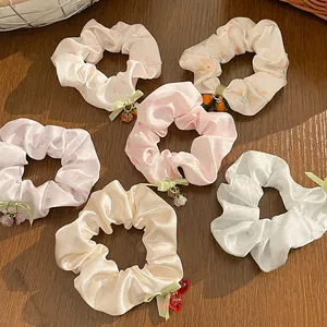 Set of six pastel floral scrunchies with silk ribbon bows and cute pendants on wood