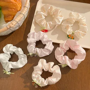 Set of 6 satin floral scrunchies with cute charms on a cozy wooden tabletop setup