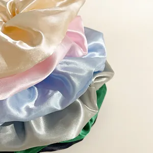 Dettaglio di elastici scrunchie giganti in raso multicolore con finitura setosa e lucida