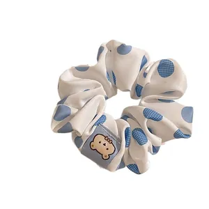 Blue polka dot scrunchie with lace edge and cute cartoon bear detail on white background