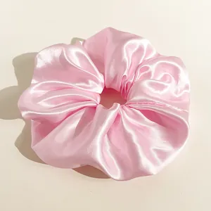 Dettaglio macro di un elastico per capelli in raso rosa con texture setosa e lucida