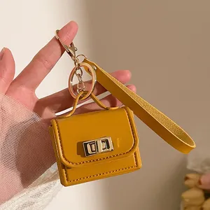 Dettaglio portachiavi a forma di mini borsa giallo senape con finiture in oro e cinturino