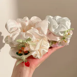 Detailed shot of satin floral scrunchies with cute strawberry and flower charms